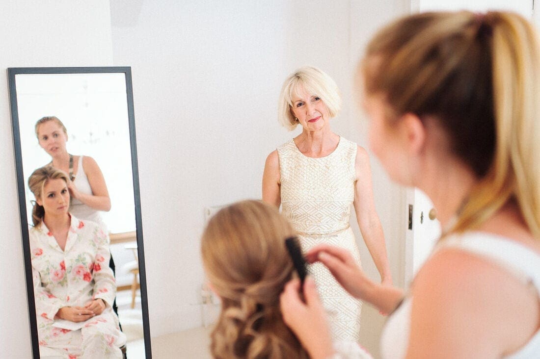 the mother of the bride looks on during the makeup session